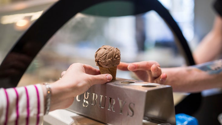 A person holds an ice cream cone in front of an ice cream counter